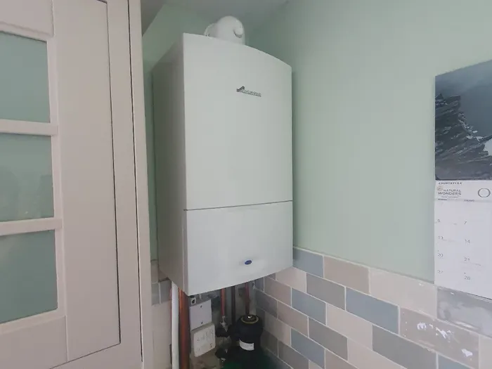 Worcester boiler fitted beside kitchen units on a sage-green wall