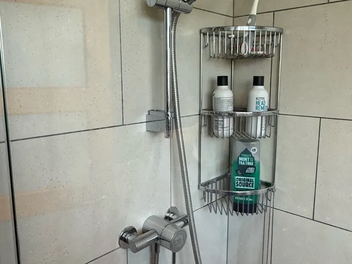 Finished corner shower enclosure with a chrome mixer and riser