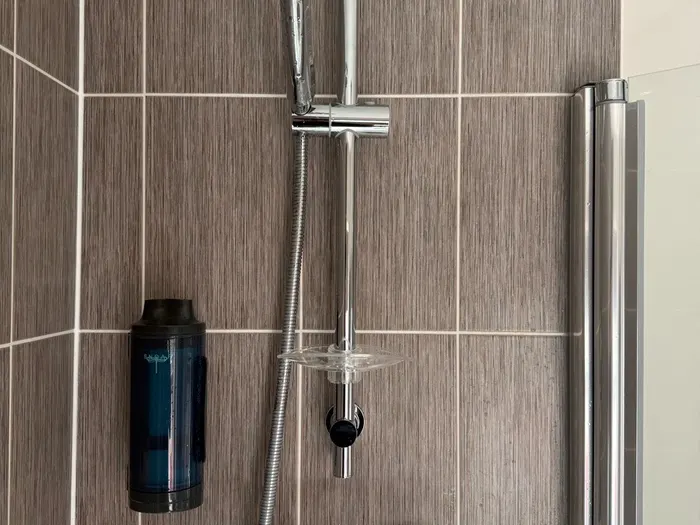 Thermostatic shower column fitted in a modern grey-tiled shower