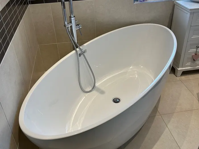 Freestanding bath with a chrome floor tap beneath a shuttered window