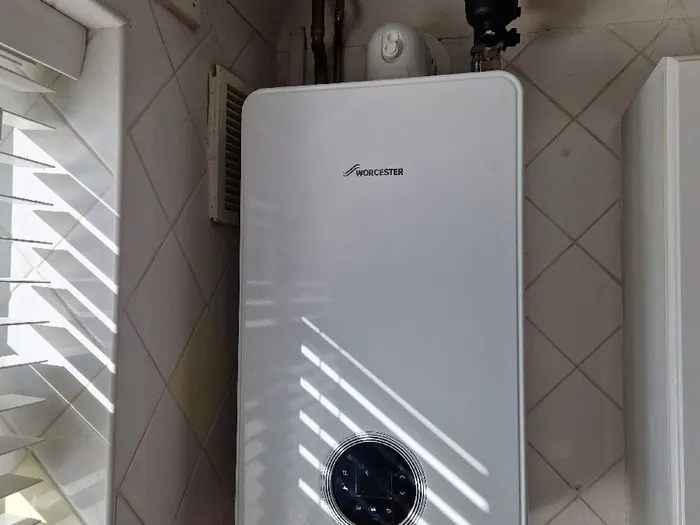 Worcester boiler on a tiled wall beside a window with blinds