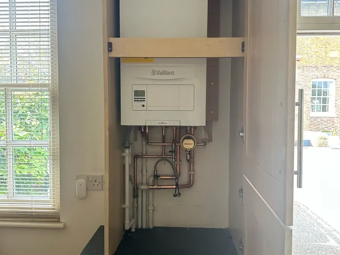 Boiler in a bright hall cupboard with tidy pipework
